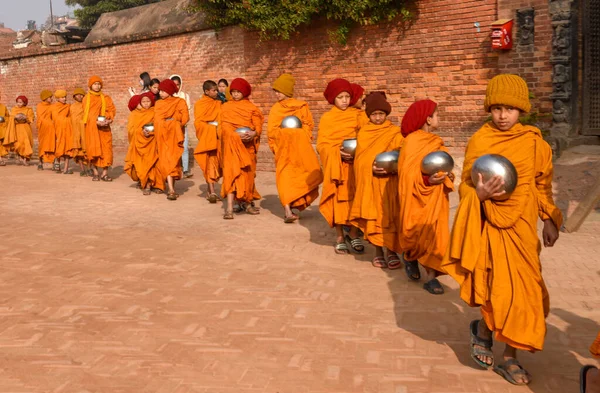 Bhaktapur, Nepal - 28 Ocak 2020: Nepal 'deki Bhaktapur' da sabah sadakalarında yürüyen genç Budist rahipler