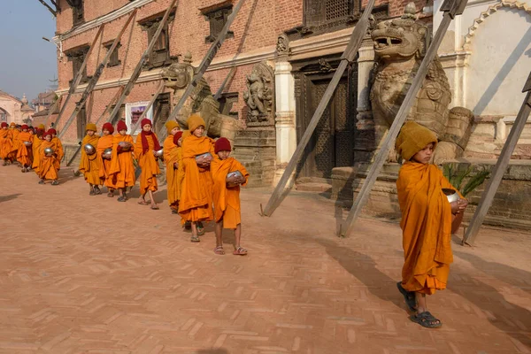 Bhaktapur, Nepal - 28 Ocak 2020: Nepal 'deki Bhaktapur' da sabah sadakalarında yürüyen genç Budist rahipler
