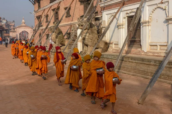 Bhaktapur, Nepal - 28 Ocak 2020: Nepal 'deki Bhaktapur' da sabah sadakalarında yürüyen genç Budist rahipler