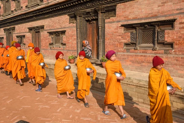 Bhaktapur, Nepal - 28 Ocak 2020: Nepal 'deki Bhaktapur' da sabah sadakalarında yürüyen genç Budist rahipler