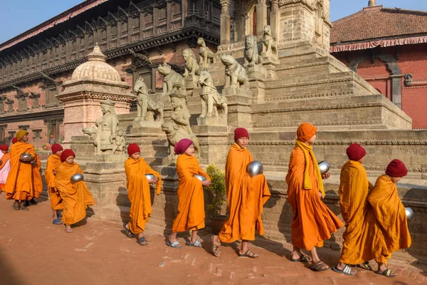 Bhaktapur, Nepal - 28 Ocak 2020: Nepal 'deki Bhaktapur' da sabah sadakalarında yürüyen genç Budist rahipler