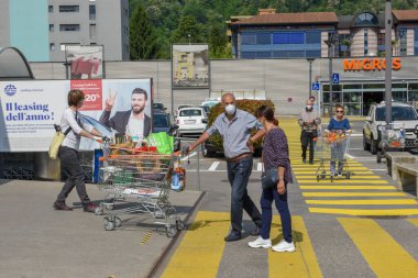 Lugano, İsviçre - 9 Mayıs 2020: İsviçre 'deki Lugano' da insanlar Coronavirus (COVID-19) nedeniyle süpermarketin önünde kuyruğa giriyorlar