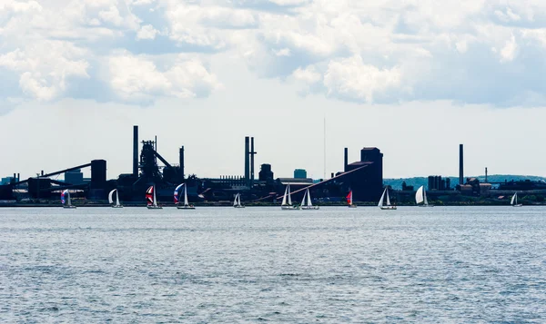 Sailboats pass by industrial area in Hamilton, Ontario, Canada.