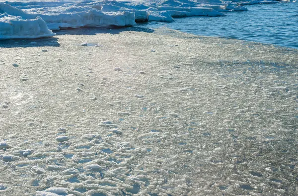 Melting ice chunks by water and frozen shore. — Stock Photo, Image