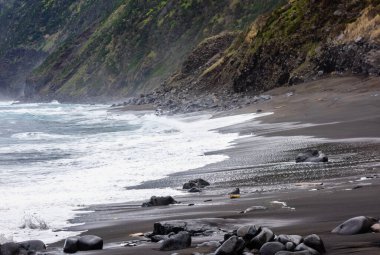Portekiz, Azores 'teki sarp kayalıkların yakınındaki ıslak sahilde okyanus dalgaları sıçrıyor..