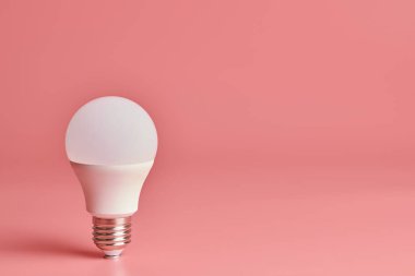 Ampul, kopyalama alanı. Enerji tasarrufu minimal fikir kavramı. Pembe arka plan.