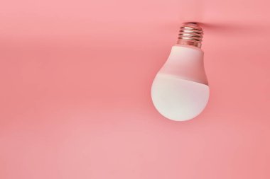 Ampul, kopyalama alanı. Enerji tasarrufu minimal fikir kavramı. Pembe arka plan.