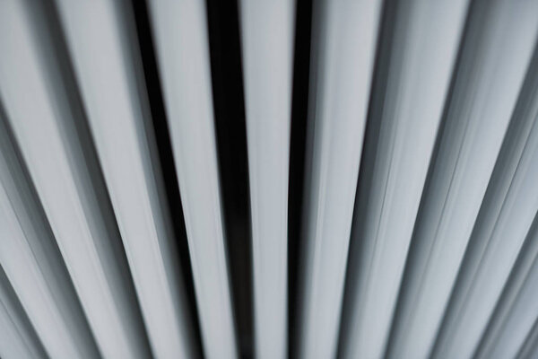 Heating radiator in office, close up. White heat exchangers. Iron aluminium steam radiator. Pipe pattern.