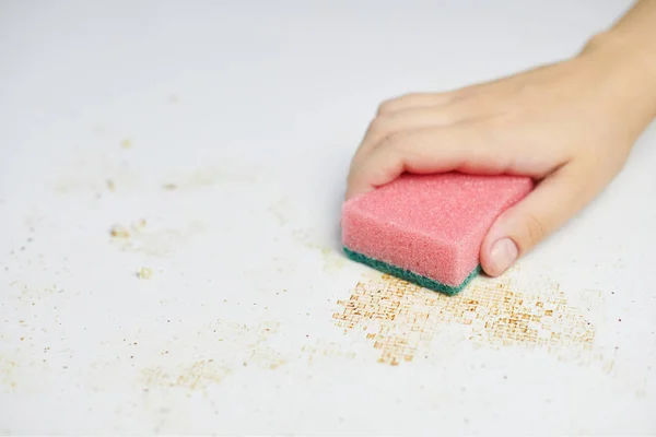 La esponja en mano de mujer elimina la suciedad, las migajas de pan y las sobras. Limpieza de mesa de cocina. Funciones domésticas —  Fotos de Stock