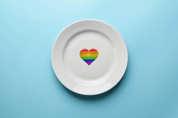 Heart in LGBT flag colors in plate. Romantic gay dating in cafe or restaurant. Waiting for special LGBT guest for wedding banquet. — Stock Photo, Image