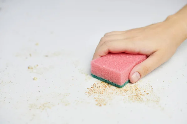 Sponge in woman hand removes dirt, bread crumbs and leftovers. Cleaning kitchen table. Household chores — Stock Photo, Image