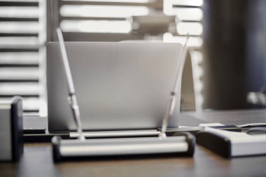 Modern ofis işyeri. İş yerinde şef, patron ya da diğer çalışanlar için iş bilgisayarı var. Defter çalışma masasında. Ofis büyük bir şirket. Işıklar yarı açık panjurlarda.