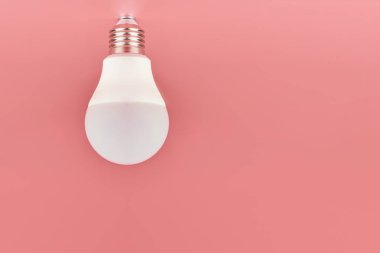 Ampul, kopyalama alanı. Enerji tasarrufu minimal fikir kavramı. Pembe arka plan.