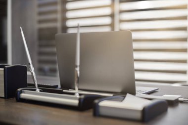 Modern ofis işyeri. İş yerinde şef, patron ya da diğer çalışanlar için iş bilgisayarı var. Defter çalışma masasında. Ofis büyük bir şirket. Işıklar yarı açık panjurlarda.