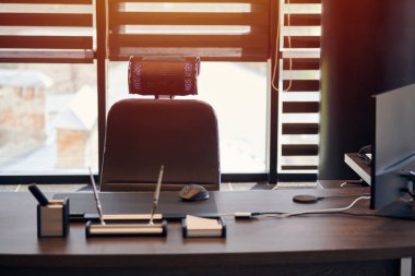 İş yeri işyeri. Şef, patron ya da diğer çalışanlar için iş yeri. Masa ve rahat sandalye. Açık panjurların arasından ışık geçiyor.