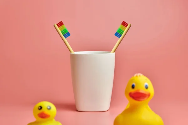 Two toothbrush and bathroom duck toys. LGBT personal care concept. Protect oral cavity, remove plaque and tartar. — Stock Photo, Image