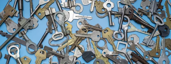 Llaves colocadas sobre fondo azul. Cerradura de puerta llaves y cajas fuertes para la seguridad de la propiedad y la protección de la casa. Diferentes tipos antiguos y nuevos de llaves . —  Fotos de Stock