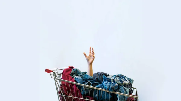 Shopaholic concept. Female hand sticks out of shopping cart — Stock Photo, Image