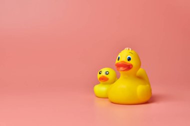 İki sarı plastik ördek oyuncağı, kopyalama alanı. Sevimli komik banyo oyuncakları, asgari kidult konsepti. Pembe arkaplan.