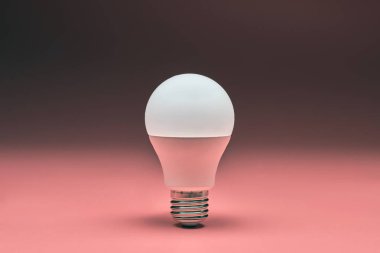 Ampul, kopyalama alanı. Enerji tasarrufu minimal fikir kavramı. Pembe arka plan.