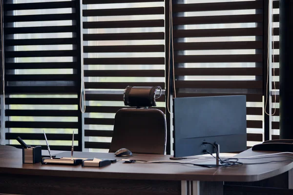 Büroarbeitsplatz. Arbeitsplatz für Chef, Chef oder andere Mitarbeiter. Tisch und bequemer Stuhl. Licht durch die halb offenen Jalousien — Stockfoto