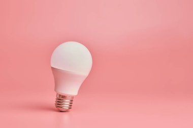 Ampul, kopyalama alanı. Enerji tasarrufu minimal fikir kavramı. Pembe arka plan.