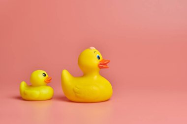 İki sarı plastik ördek oyuncağı, kopyalama alanı. Sevimli komik banyo oyuncakları, asgari kidult konsepti. Pembe arkaplan.