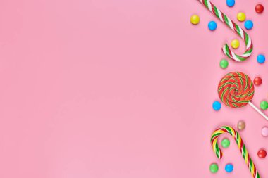 Tatlı, lolipop ve pembe arka planda şeker kamışı, kopyalama alanı. Çocukluk konseptinde renkli tatlılara bayılırım.