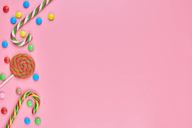 Tatlı, lolipop ve pembe arka planda şeker kamışı, kopyalama alanı. Çocukluk konseptinde renkli tatlılara bayılırım.