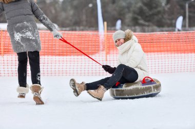 Reshetikha, Rusya - 02.02.2019 Mutlu genç kız kar üzerinde kayıyor. Çocuklar ve gençler için kar hortumlama oyunları.