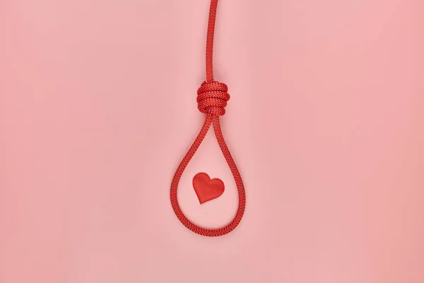 Heart in hangman\'s knot. Unrequited love hanging suicide concept. Red braided hanging noose tied the knot. Failed Valentine\'s day symbol
