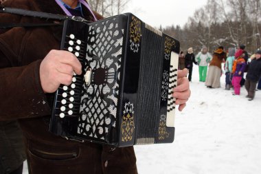 The musician plays accordion in winter weather on the feast of carnival.                                clipart