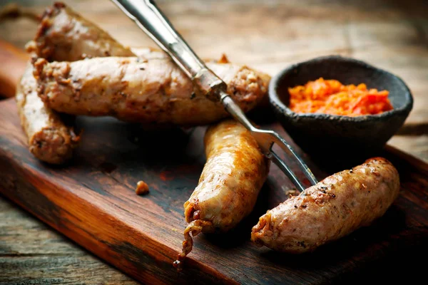Merguez Sausages with harissa on wooden board — Stock Photo, Image