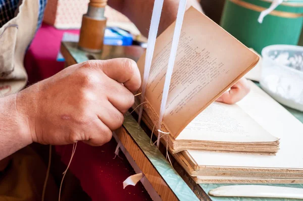 Buchbindung. männliche Arbeiter binden Seiten ein. — Stockfoto