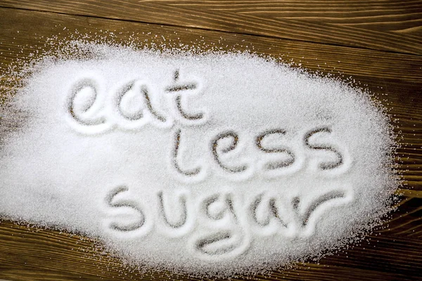 EAT LESS SUGAR написаний на купі цукру — стокове фото