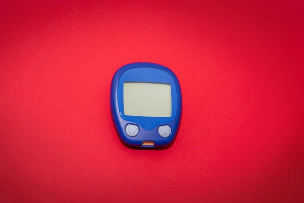 Prázdné glukometr na červeném pozadí — Stock fotografie