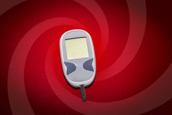 Leeres Glukometer auf rotem Hintergrund — Stockfoto