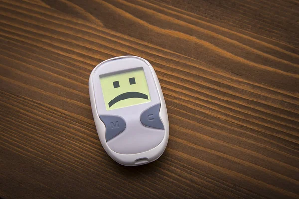 Sad glucometer on wooden background — Stock Photo, Image