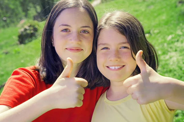 Portrait of pretty teenage sisters showing thumbs up — Stock Photo, Image
