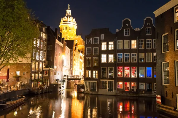 Red light district at night, Dom of the Church of St. Nicholas is illuminated at night, the Netherlands.