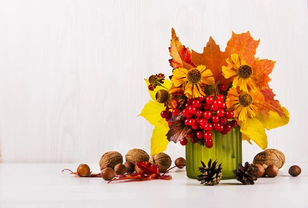 Bouquet autunnale in vaso, frutti di bosco, noci su uno sfondo di legno bianco — Foto Stock