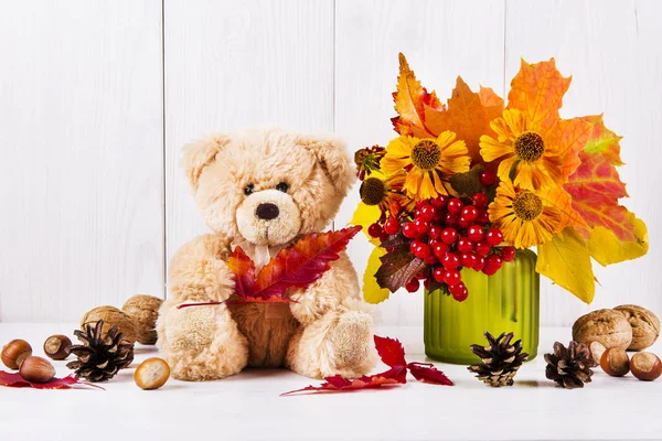 Ramo de otoño en un jarrón, bayas, nueces, oso de peluche en woo blanco —  Fotos de Stock
