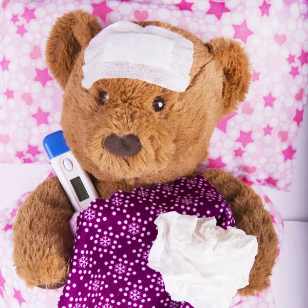 Sick teddy bear wrapped in bandages with underarm thermometer