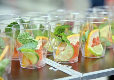 Plastik bardakta mojito. 2 şişe mojito şurubu. Mojito içerikli boş bardaklar. Bardakta buz küpleri. Sıvı nitrojenden gaz.