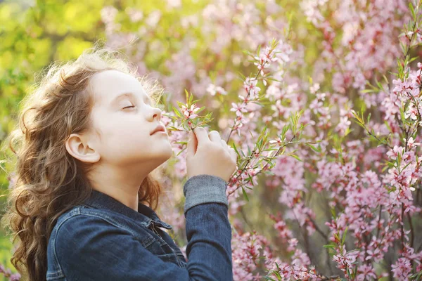 Cute girl enjoys the smell of blossoming almond flower. Healthy,