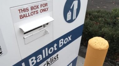 Person delivering voter's ballot to ballot box during election day.
