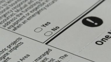 Person using pen in hand to make a no vote on voter's ballot, close up.