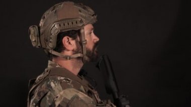 Man dressed in military uniform turns and looks to camera.