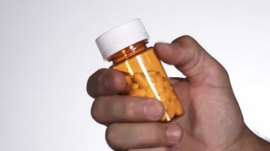 Person opens prescription bottle and pours out all the pills, no branding and in studio.