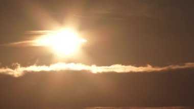 Timelapse of sunset falling behind cloud layer turning sky from bright to night.